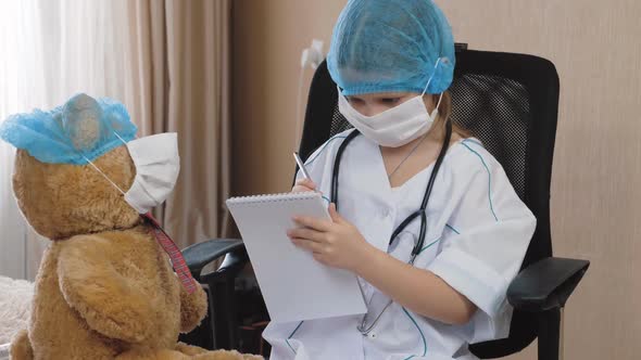 Little girl in medical mask playing doctor, nurse at home. Patient diagnosis. alt