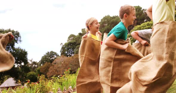 Kids having a sack race in park alt