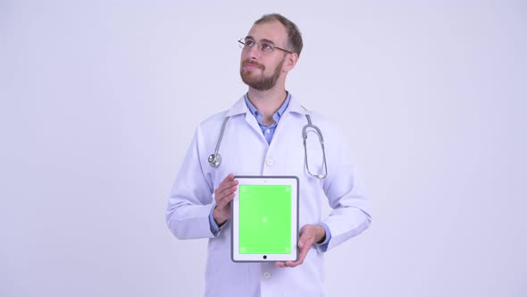 Happy Bearded Man Doctor Thinking While Showing Digital Tablet