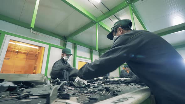 Junkyard Workers Are Sorting Fragments of Waste on a Conveyor alt