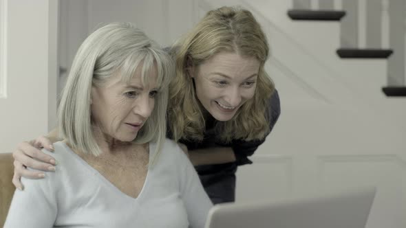 Senior Adult female looking at laptop with mature daughter