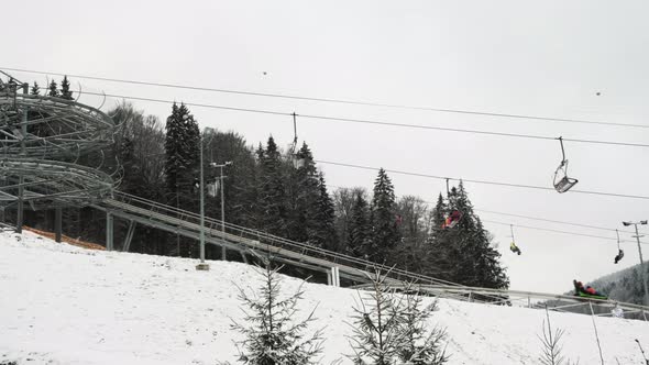 Chair Lifts Rodelbahn Alpine Coaster in Motion at Ski Resort on Winter Daytime Side View alt