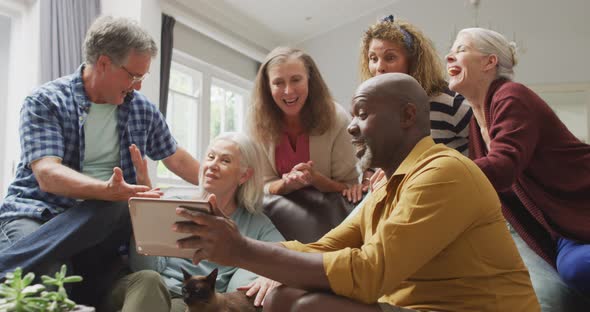 Animation of happy diverse female and male senior friends using tablet at home alt