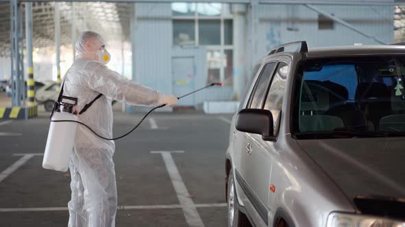 Man Dressed White Protective Overalls Spraying Vehicle Antibacterial Sanitizer Sprayer on Quarantine alt