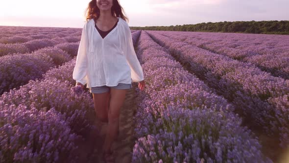 Young Woman in White Shirt Walking in Beautiful Lavender Field alt