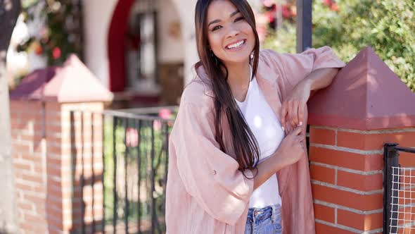 Smiling Stylish Brunette Leaning on Fence alt