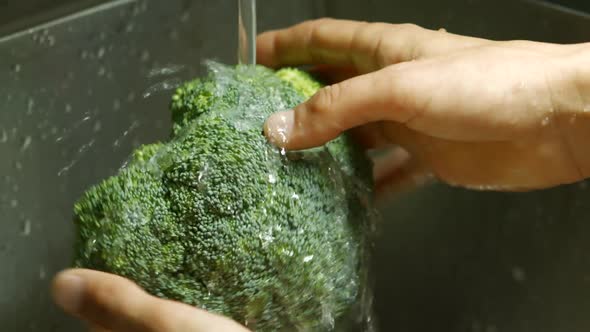 Male Hands Washing Broccoli. alt