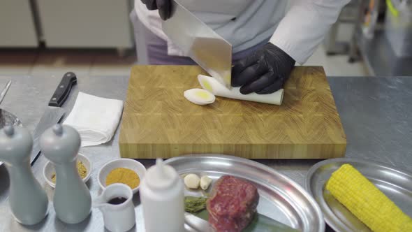 Chefs Hands in Black Latex Gloves Cutting Slices of Lemon Grass in Cutting Board alt