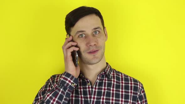A Funny, Cute Guy Makes a Phone Call on His Smartphone. A Portrait of a Young Guy, He Is Actively