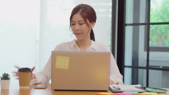 Asian business woman working with laptop and smile looking at camera alt