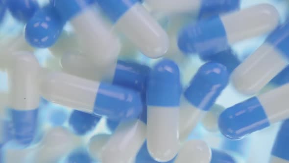 White And Blue Capsules Of The Medication Is Falling Down Into The Camera