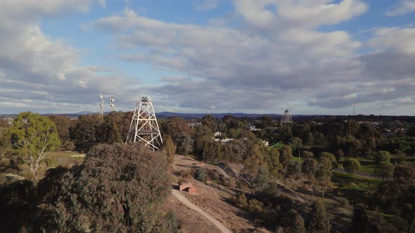 Wide circling drone shot of Victoria Hill Mining Reserve poppet head in Bendigo. Radio tower and a s alt