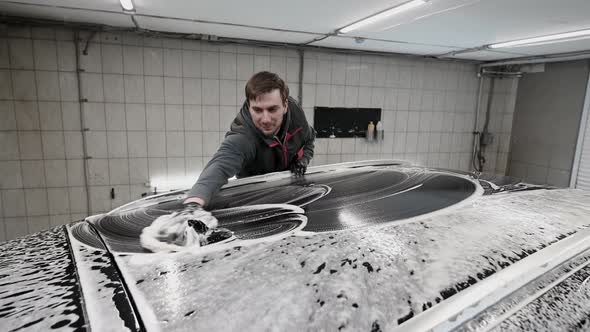 Close Up Male Hand in Black Glove with Foam Sponge Washing Car Roof