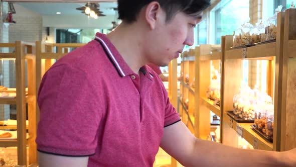 Mid Shot of Asian Young Man Shopping and Consider Buying Stuff in Retail Grocery Store alt