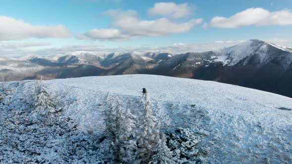 Drone Following Man Hiker Walking on Snow Covered Mountain Top