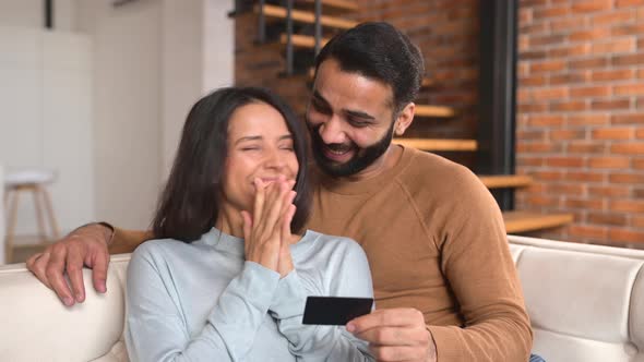 Cheerful Indian Couple Watching at Laptop Screen and Smiling Toothy Shopping Online