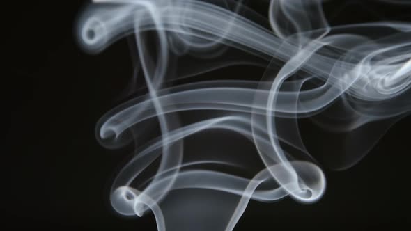 Curly line of smoke lifts up on a dark background