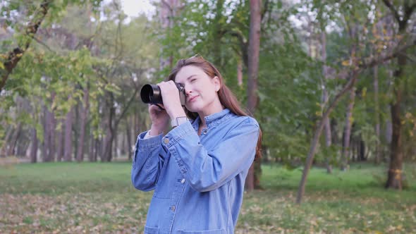 Portrait of a Young Beautiful Woman Freelancer in an Autumn Park with a Camera