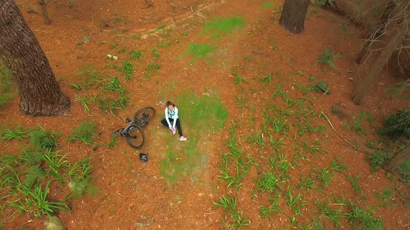 Female mountain biker fallen from her bicycle in the forest alt