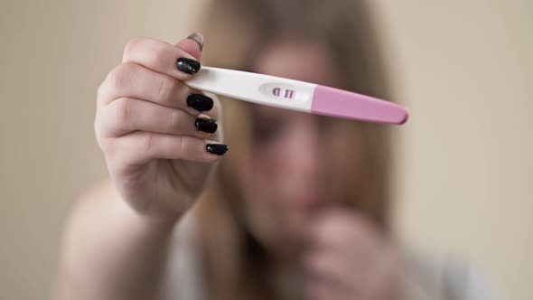 Teenage Girl Shows a Strip Test for Pregnancy alt