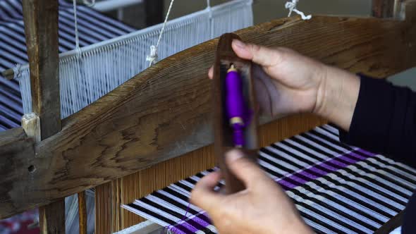 Hands of a woman work on weaving loom machines in a mountain village, Vietnam alt
