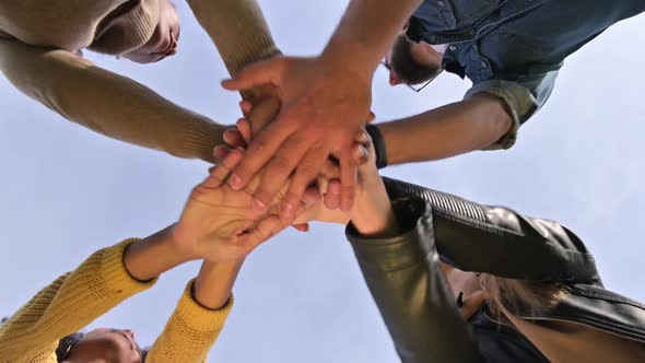 The team puts their hands together and shakes against the sky. Unity conception alt