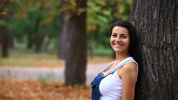 Young happy woman next to tree in in autumn park