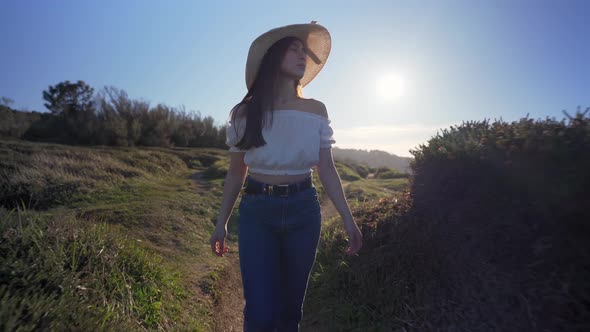 Woman walking on verdant grassy countryside alt