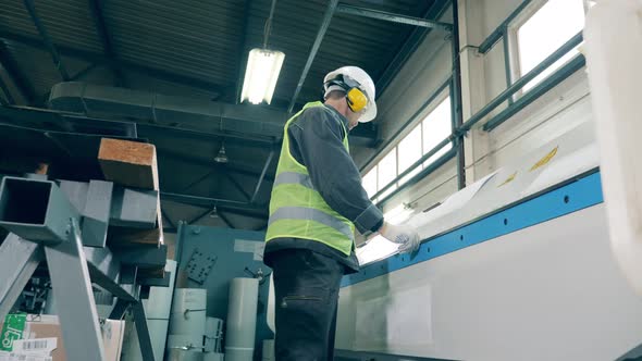 Factory Machine Is Bending Edges of Metal Under Worker's Control alt