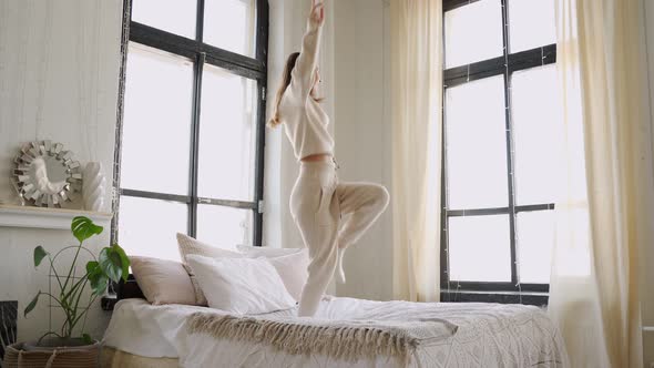 Young Woman Jumps on the Bed in the Bedroom of Her Home alt