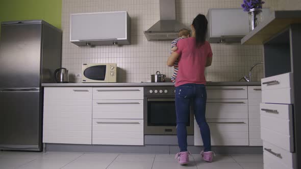 Pretty Mother Dancing with Happy Baby in Kitchen alt