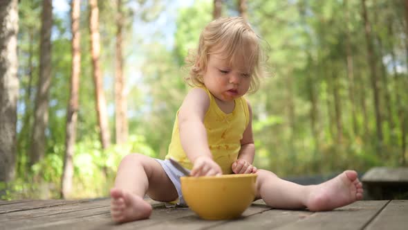 Little Funny Cute Blonde Girl Child Toddler with Dirty Clothes and Face Eating Baby Food Fruit or