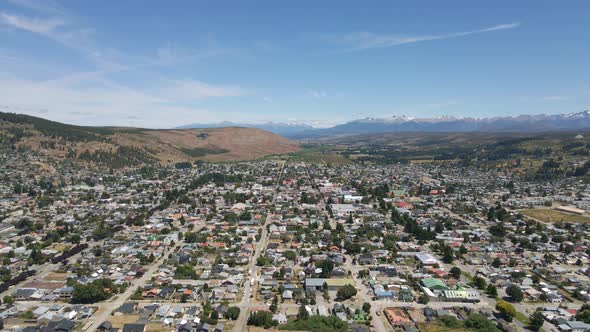 Pan right lowering over Esquel town with Andean mountains in background, Patagonia Argentina alt