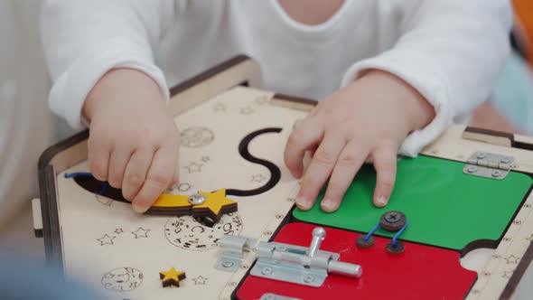 Cute Toddler Playing with Learning Toy Wooden Busy House in Kids Activity Centre Safety Play Yard alt