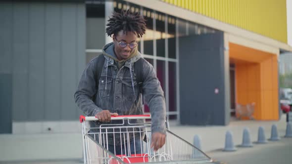Smiling Happy Young African American Man with Dreadlocks Walking From Supermarket with Shopping Bags alt