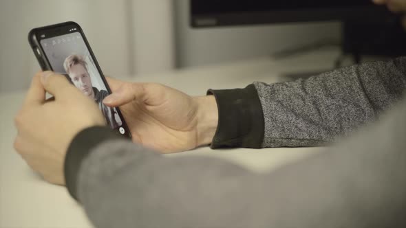 Close up of a man scrolling through selfie filters on his phone camera app alt