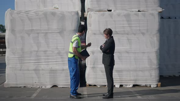 Wide Shot Confident Middle Eastern Warehouse Worker in Uniform Persuading Caucasian Inspector in alt