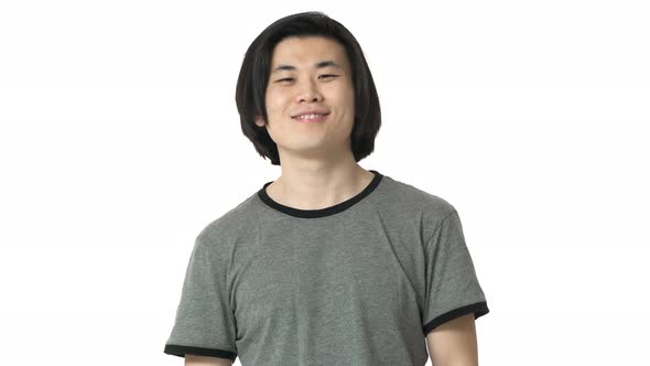 Portrait of Attractive Chinaman with Clean Skin and Dark Hair in Casual Gray Tshirt Nodding in alt