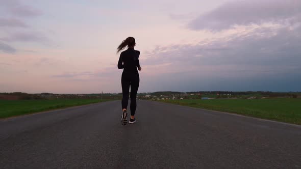 Young Woman Running on a Rural Road During Sunset