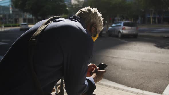 African american senior man wearing face mask using smartphone on the road alt