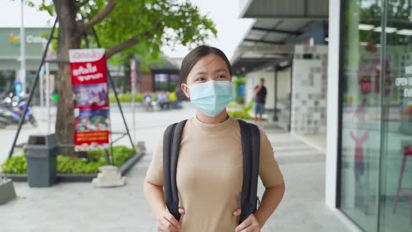 Asian woman wearing protective face mask walking at park.