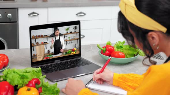 Man Chef in Laptop Screen Greets Tells Teaches Housewife Remote Cooking Lesson alt