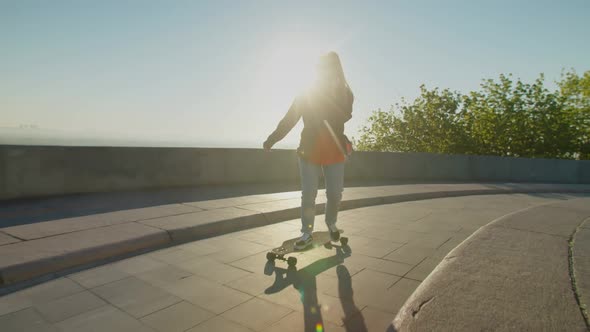 Cool Lovely Woman Skateboarding and Chatting on Cellphone at Sunrise alt