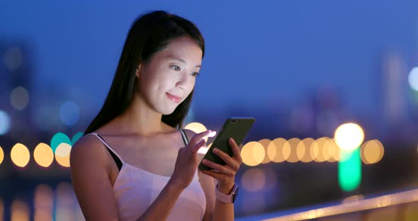Young Woman use of mobile phone in city at night alt