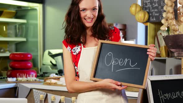 Portrait of a female staff holding a open sign alt