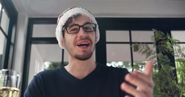Cheerful handsome man wearing hat having video call celebrating Christmas online