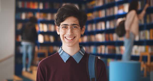 Portrait of Caucasian Male Student Smiling at Camera in School Library alt