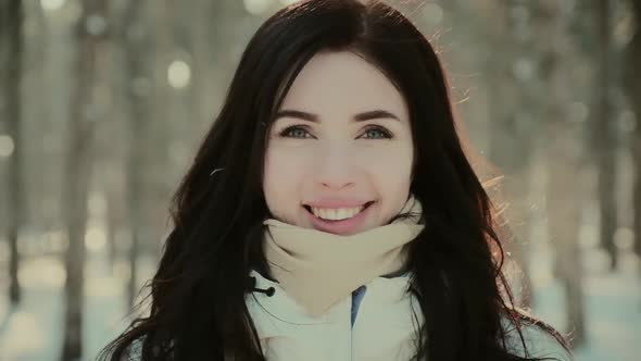 Attractive Woman in Jacket and Scarf Smiles in Winter Forest