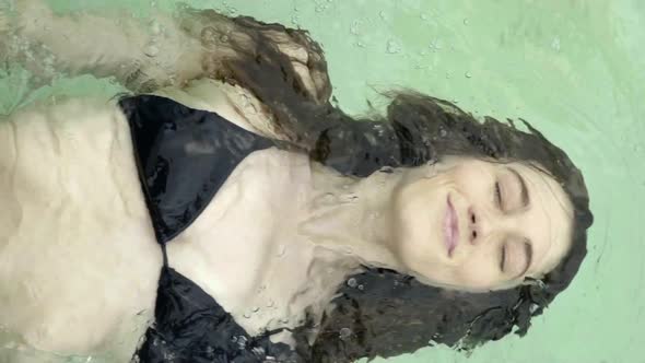 Young woman floating on back in pool with eyes closed
