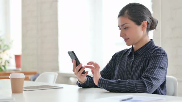 Young Indian Woman Celebrating Success on Smartphone  alt